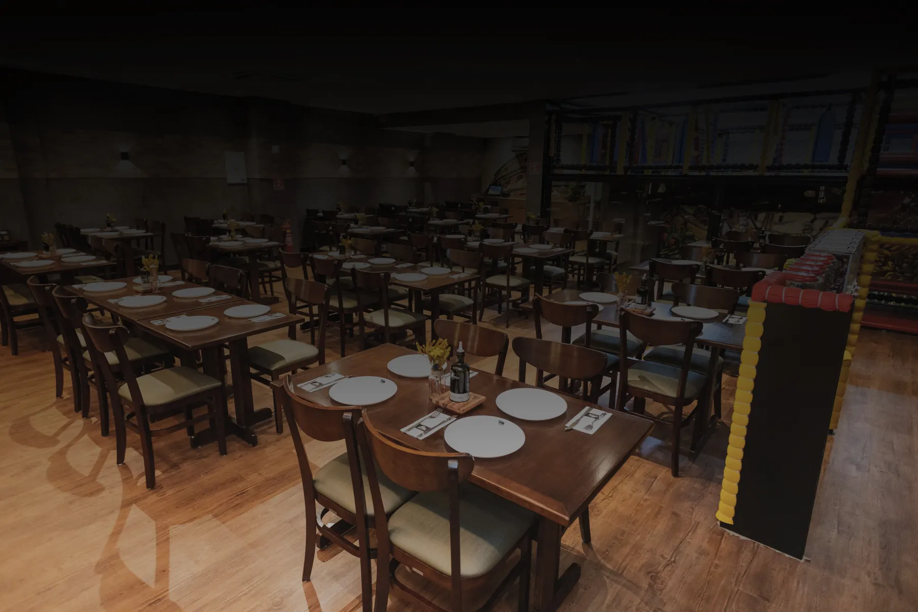 Salão da Pizzaria Fellice com mesas postas em madeira